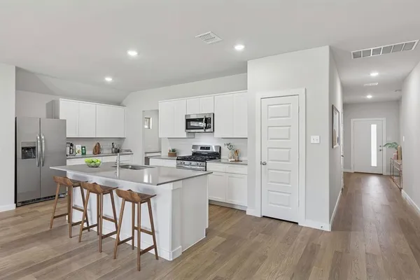a kitchen with stainless steel appliances a stove a sink cabinets and wooden floor