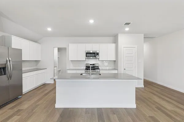 a large kitchen with stainless steel appliances a large counter top a stove and a refrigerator