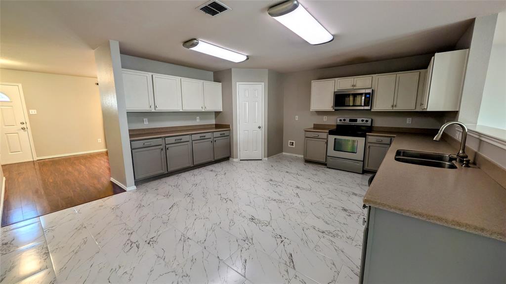 1308 Lamar Lane Allen, TX 75002 - Photo 7 of 40 Kitchen with light marble finish floors, stainless steel appliances, gray cabinetry, and white cabinets