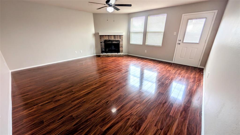 1308 Lamar Lane Allen, TX 75002 - Photo 9 of 40 Unfurnished living room with dark wood-style flooring, a brick fireplace, and ceiling fan