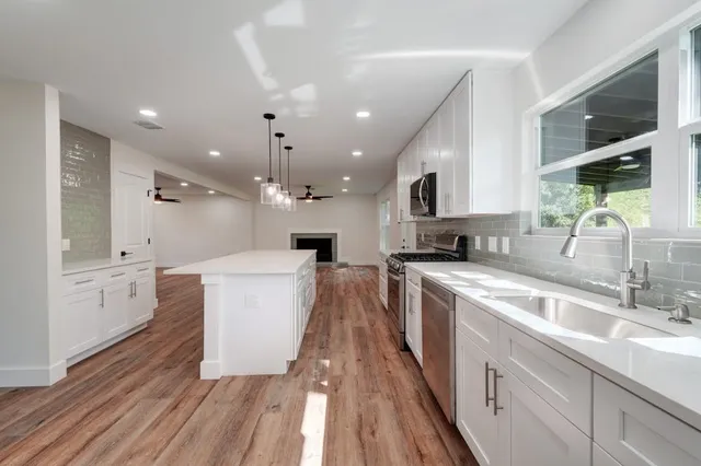 a large kitchen with granite countertop a large counter top a sink stainless steel appliances and cabinets