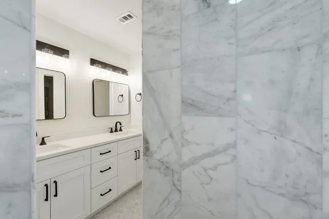 a bathroom with a double vanity sink mirror and shower