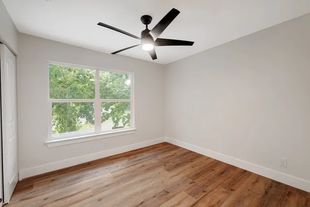 a view of empty room with wooden floor and fan