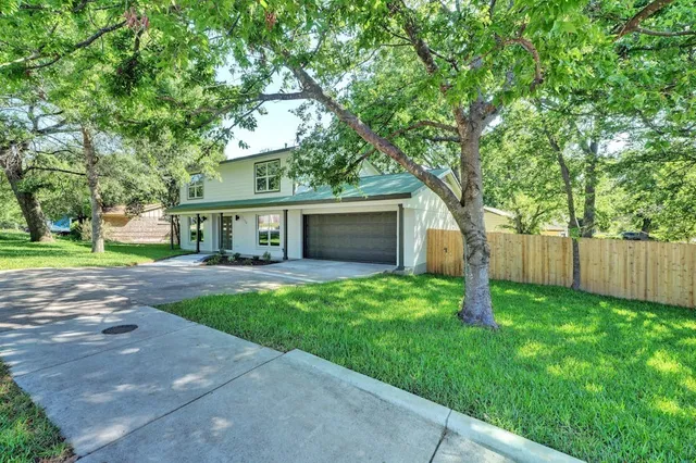 a front view of a house with a garden and trees