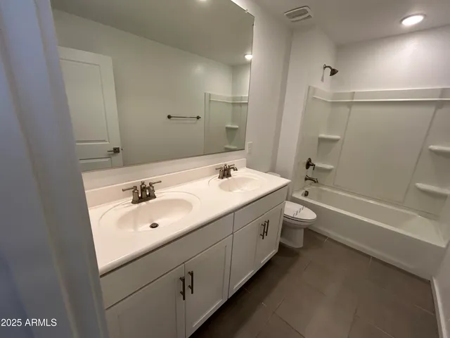 a bathroom with a double vanity sink toilet mirror and bathtub