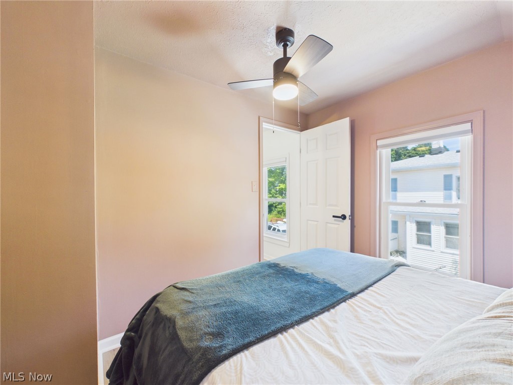 3490 County Line Road Madison, OH 44057 - Photo 33 of 42 Bedroom featuring a ceiling fan with integrated lighting, white trim around windows and door, and neutral wall tones