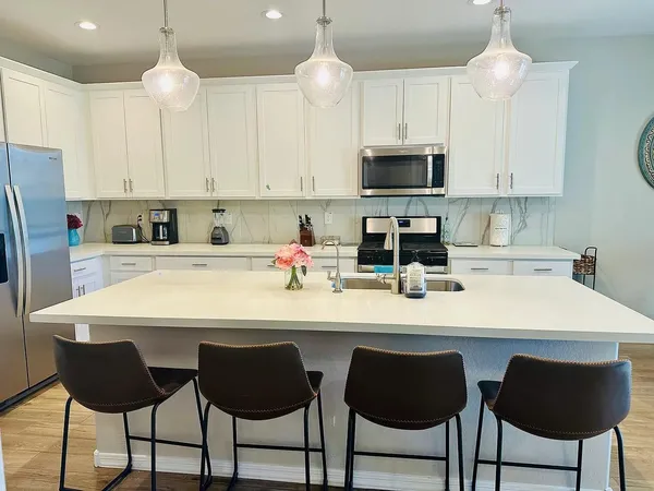 a kitchen with stainless steel appliances a white table and chairs in it