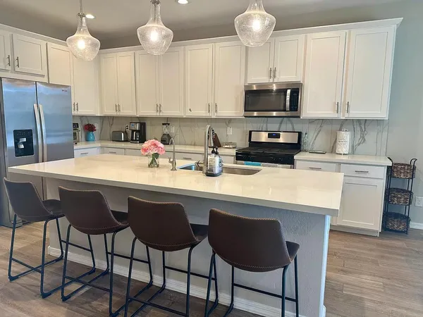 a kitchen with a sink a stove a refrigerator and white cabinets