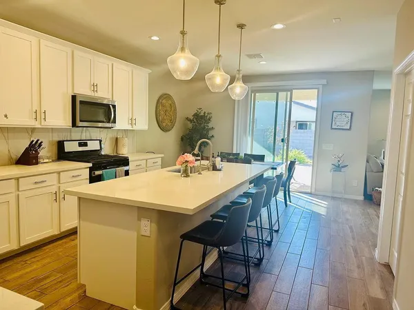 a kitchen with a stove a sink a kitchen island with a dining table and chairs