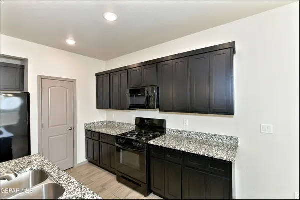a kitchen with granite countertop stainless steel appliances a stove sink and cabinets