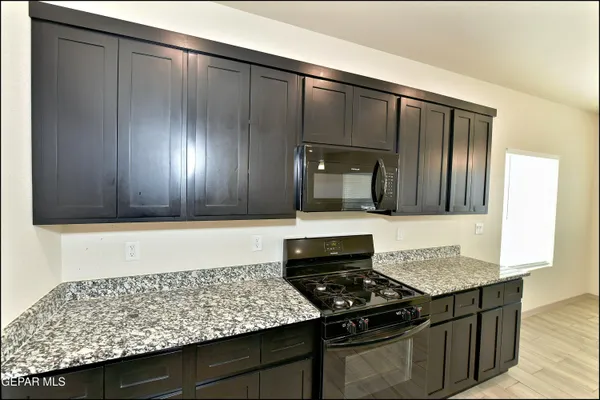 a kitchen with granite countertop cabinets and stove top oven