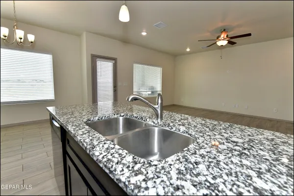 a kitchen with a granite countertop sink a mirror and chandelier