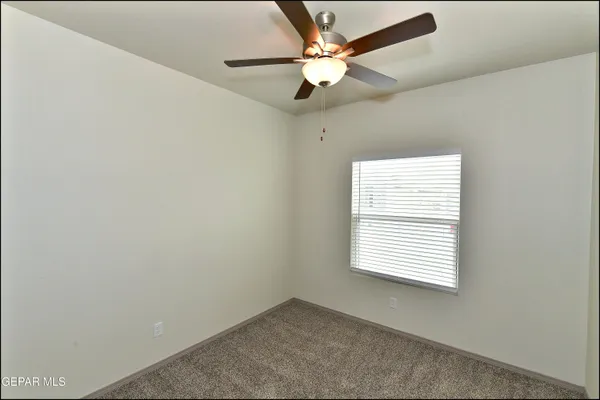 an empty room with closet and a ceiling fan
