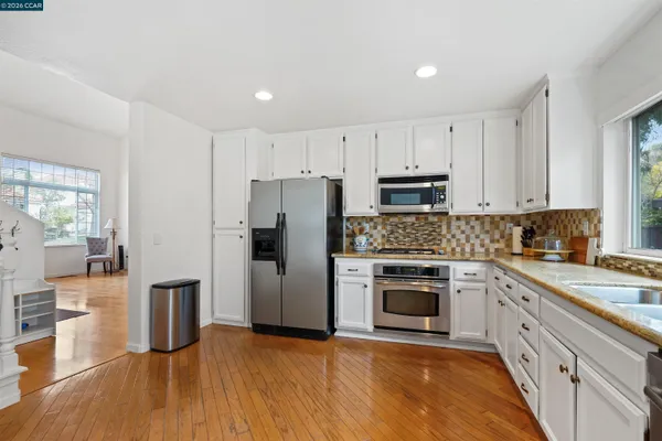 a kitchen with cabinets stainless steel appliances and wooden floor