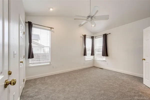 an empty room with chandelier fan and windows