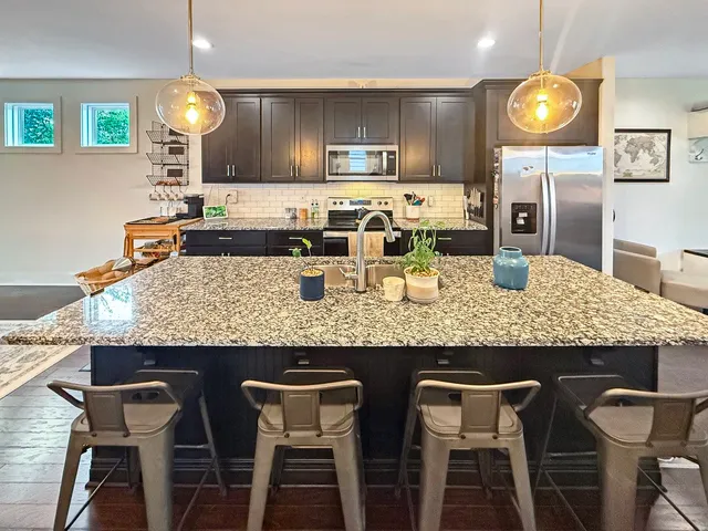 a kitchen with granite countertop kitchen island stainless steel appliances a table and chairs in it