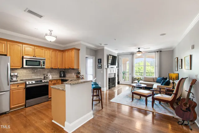 a kitchen with stainless steel appliances granite countertop a stove top oven a sink dishwasher a dining table and chairs with wooden floor