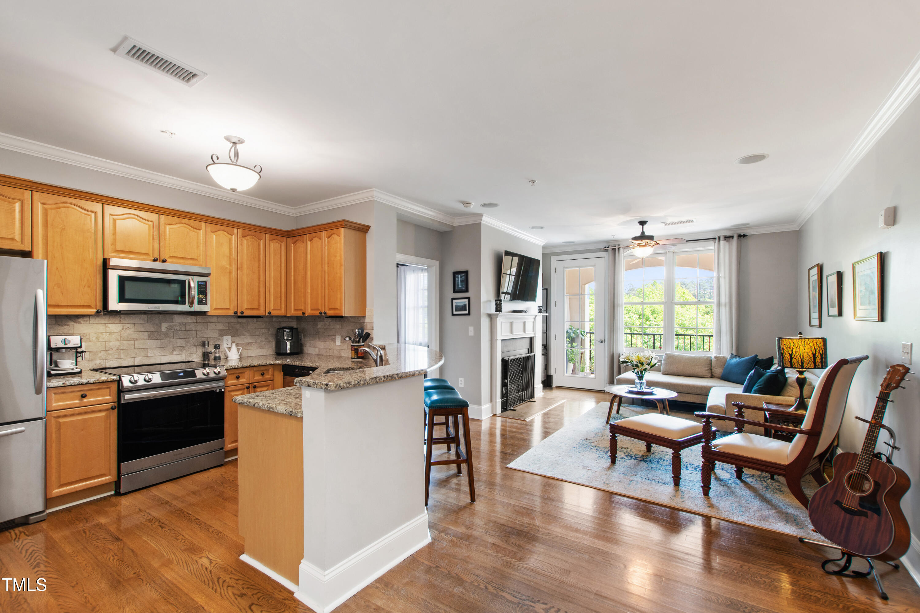 a kitchen with stainless steel appliances granite countertop a stove top oven a sink dishwasher a dining table and chairs with wooden floor