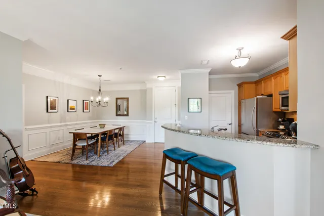 a living room with stainless steel appliances furniture a dining table and chairs with wooden floor