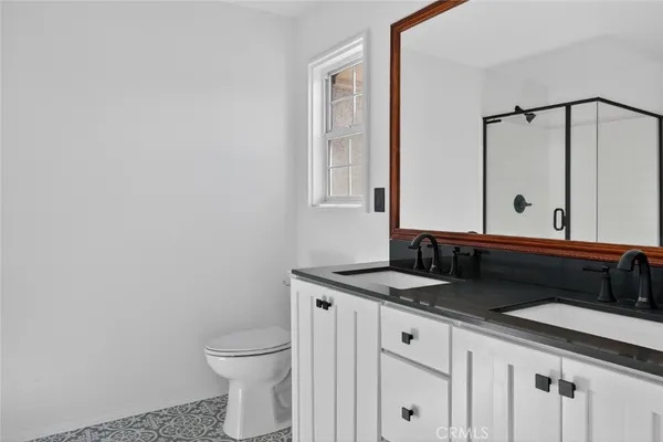 a bathroom with a granite countertop sink a toilet and a mirror
