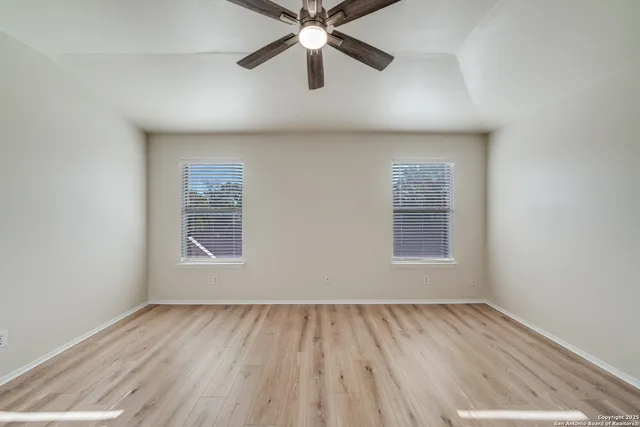an empty room with a window and a ceiling fan