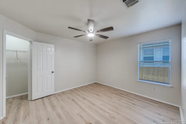 a view of empty room with wooden floor and fan