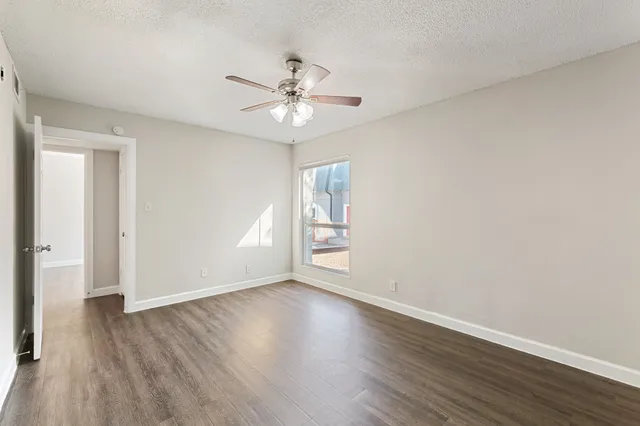 a view of an empty room with a window and wooden floor