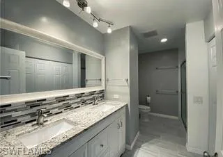 a bathroom with a granite countertop sink a toilet and a shower