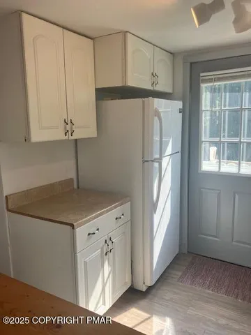 a kitchen with white cabinets and a refrigerator