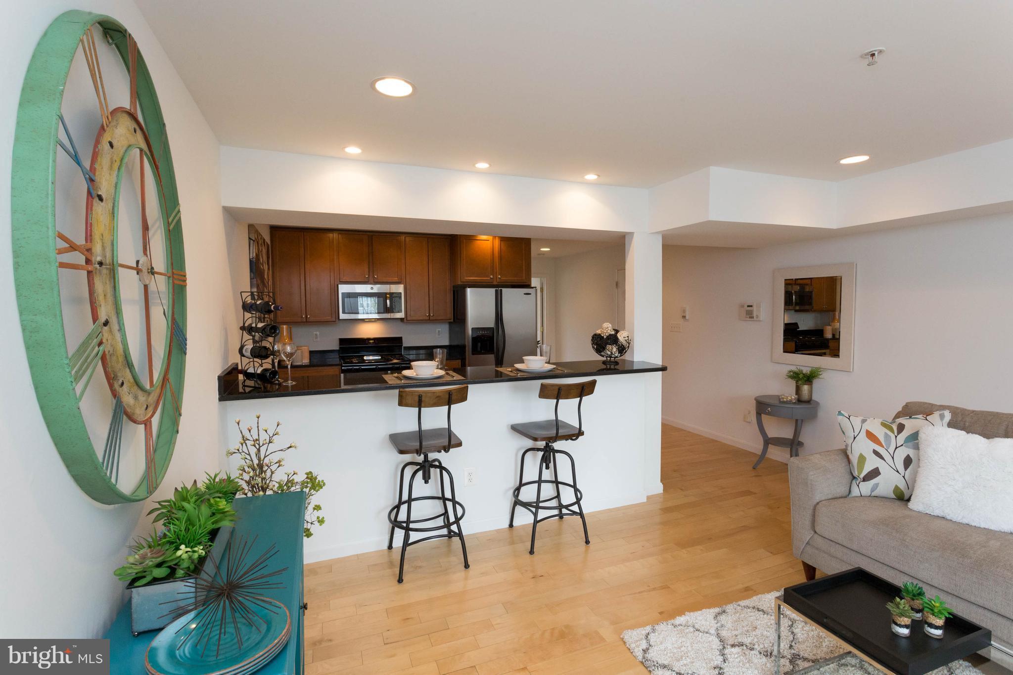 a view of kitchen with stainless steel appliances granite countertop dining table chairs and a refrigerator