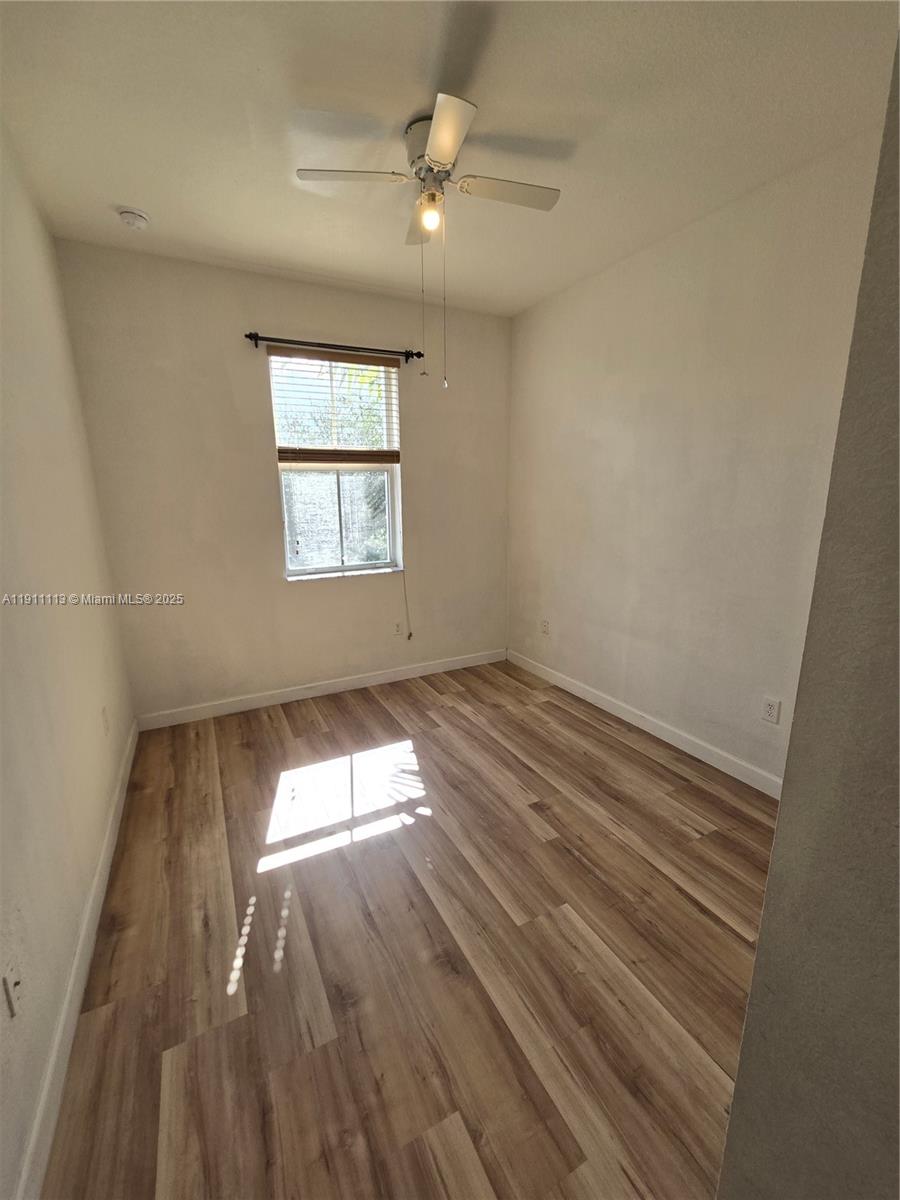 988 Southwest 154th Path Miami, FL 33194 - Photo 17 of 31 an empty room with wooden floor chandelier fan and windows