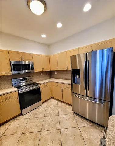 a large kitchen with cabinets a sink and stainless steel appliances