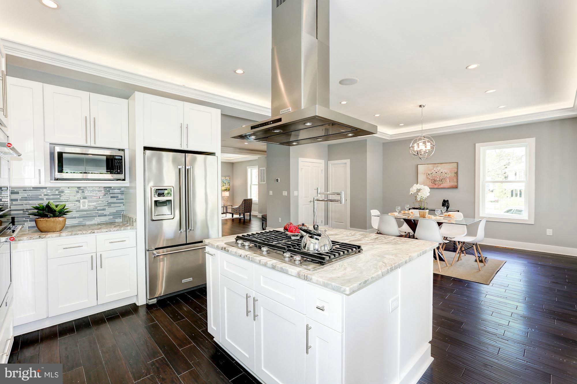 a kitchen with a refrigerator a stove a sink and white cabinets with wooden floor