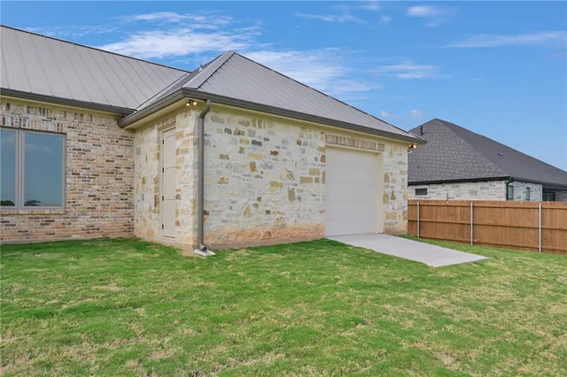 a view of a house with a yard and a large tree