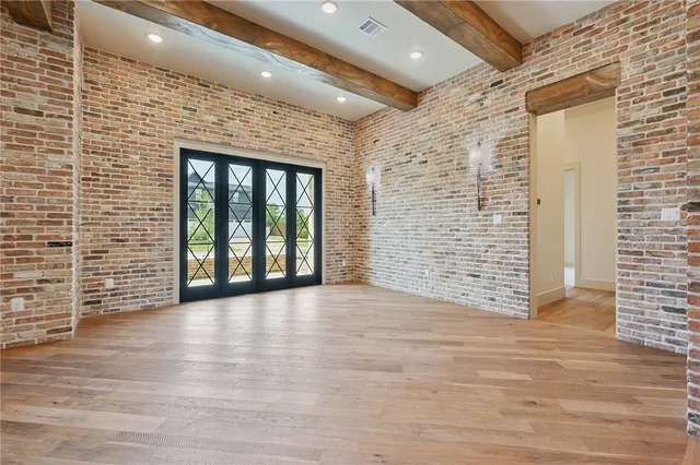 a view of an empty room with wooden floor and a kitchen