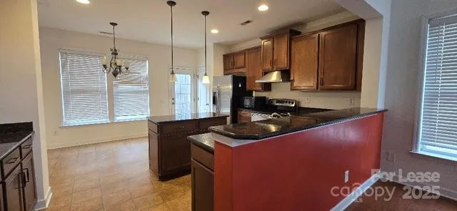 a kitchen with kitchen island granite countertop a sink stove and refrigerator