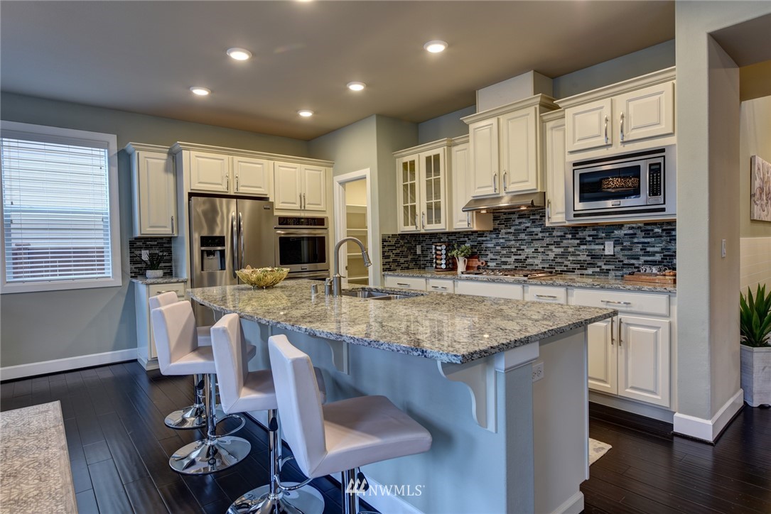 4130 174th Street Southeast Bothell, WA 98012 - Photo 3 of 29 a kitchen with stainless steel appliances granite countertop a sink dishwasher stove refrigerator and cabinets with wooden floor