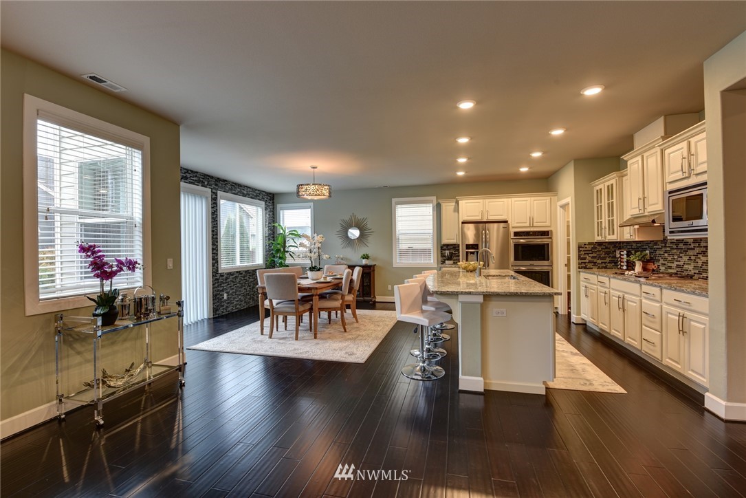 4130 174th Street Southeast Bothell, WA 98012 - Photo 5 of 29 a living room with stainless steel appliances kitchen island granite countertop a stove a sink a refrigerator and white cabinets with wooden floor