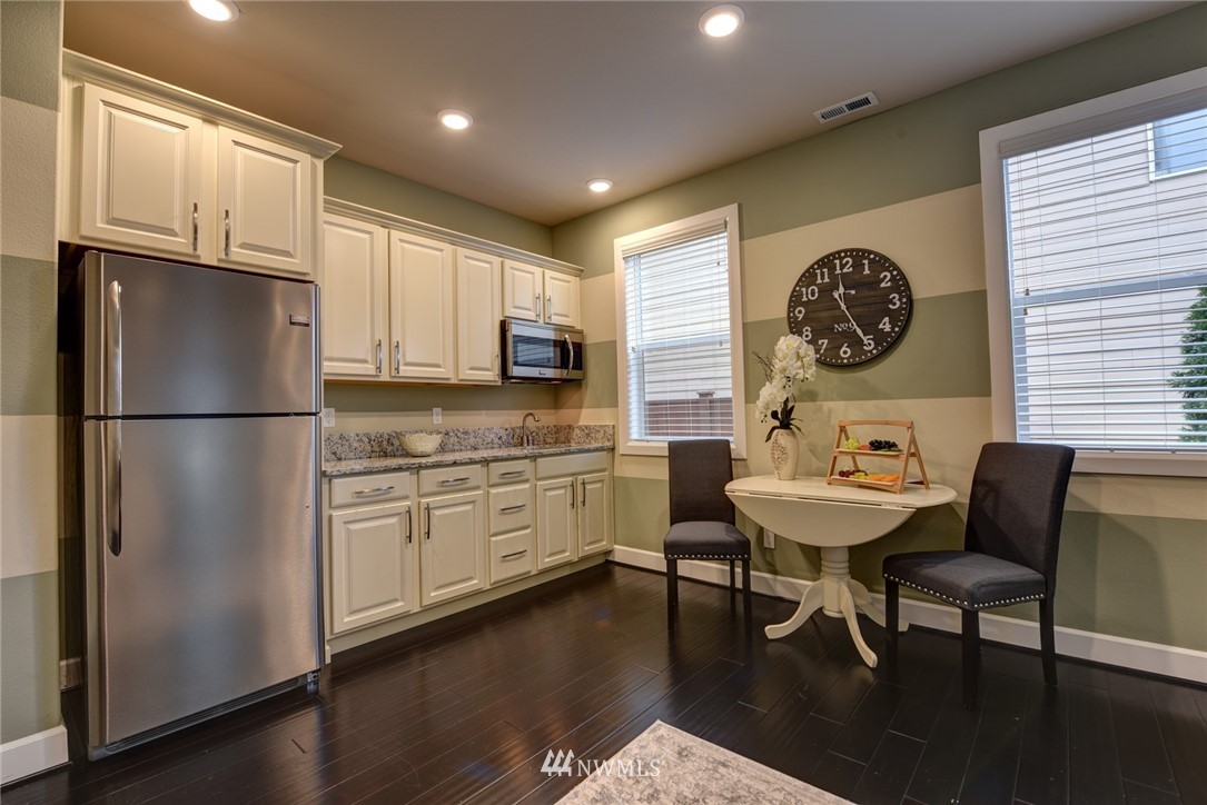 4130 174th Street Southeast Bothell, WA 98012 - Photo 10 of 29 a kitchen with stainless steel appliances granite countertop a refrigerator a stove a sink a dining table and chairs with wooden floor