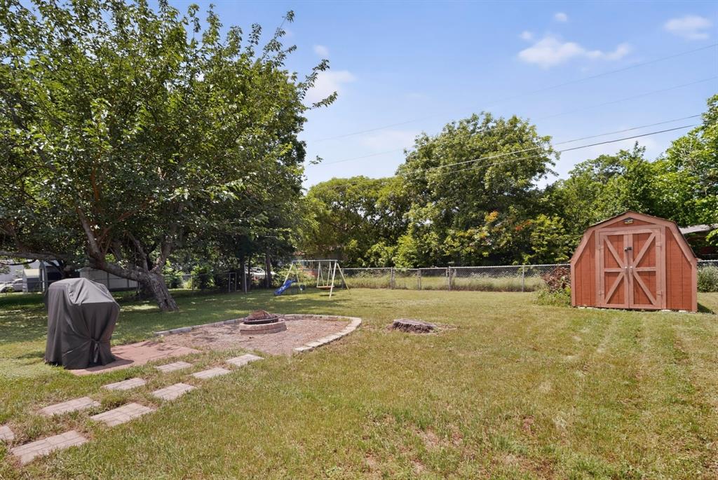 321 Redbud Street Rhome, TX 76078 - Photo 16 of 17 Backyard offers plenty of space with fire pit, mature tree, and storage shed.