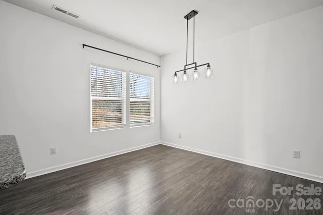 a kitchen with stainless steel appliances kitchen island granite countertop a refrigerator a stove a sink dishwasher a refrigerator and a dining table with wooden floor