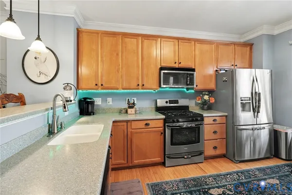 a kitchen with stainless steel appliances granite countertop a refrigerator a stove a sink dishwasher and a dining table with wooden floor