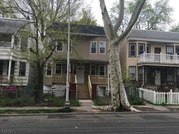 a front view of a house with a tree