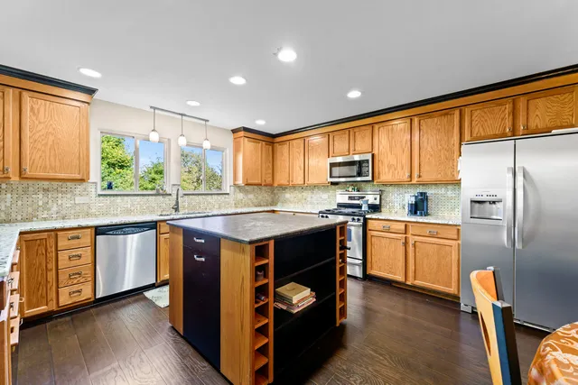 a kitchen with stainless steel appliances granite countertop wooden cabinets a center island and a refrigerator