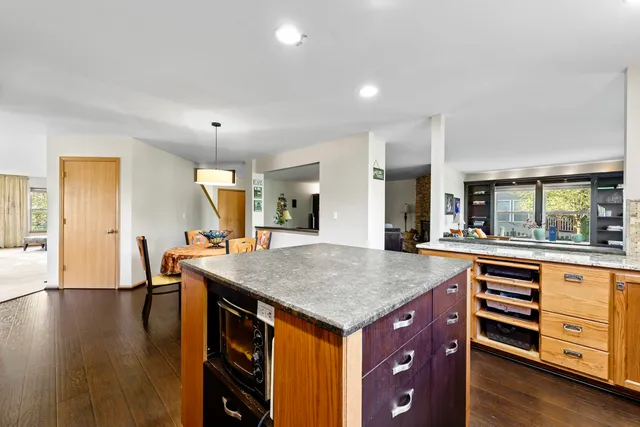 a kitchen with stainless steel appliances granite countertop a refrigerator a stove top oven and a dining table with wooden floor