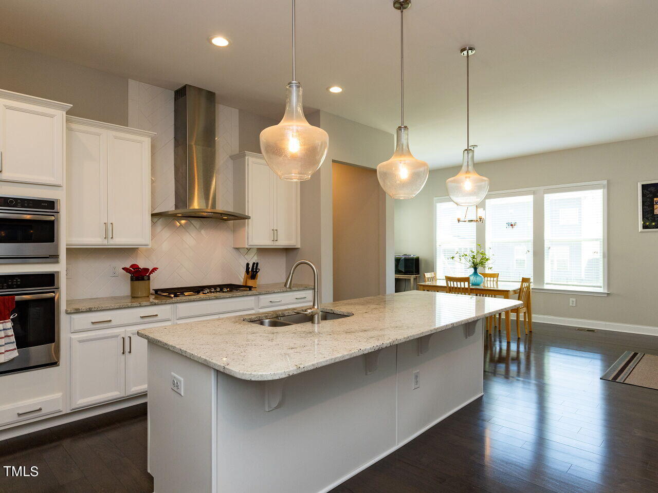 605 White Oak Pond Road Apex, NC 27523 - Photo 11 of 46 a open kitchen with stainless steel appliances granite countertop a sink a stove and a wooden floors