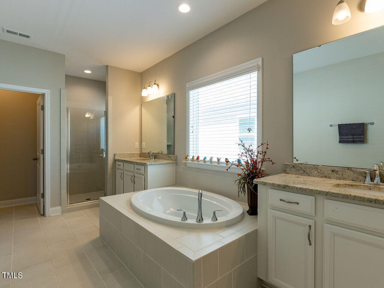 605 White Oak Pond Road Apex, NC 27523 - Photo 28 of 46 a bathroom with a granite countertop sink a mirror a bathtub and shower