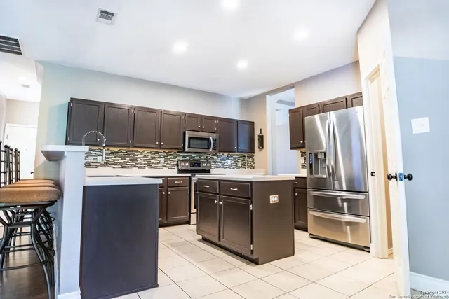 a kitchen with stainless steel appliances kitchen island granite countertop a refrigerator and a stove top oven