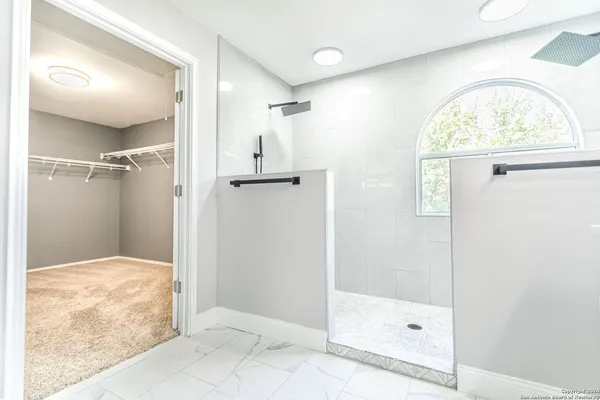 a view of a livingroom with a chandelier fan and kitchen view