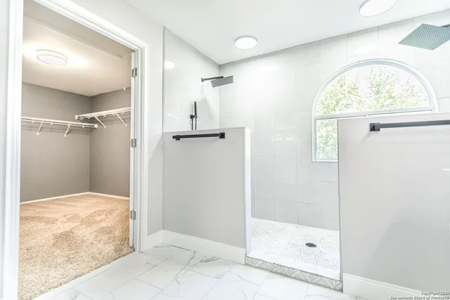 a view of a livingroom with a chandelier fan and kitchen view